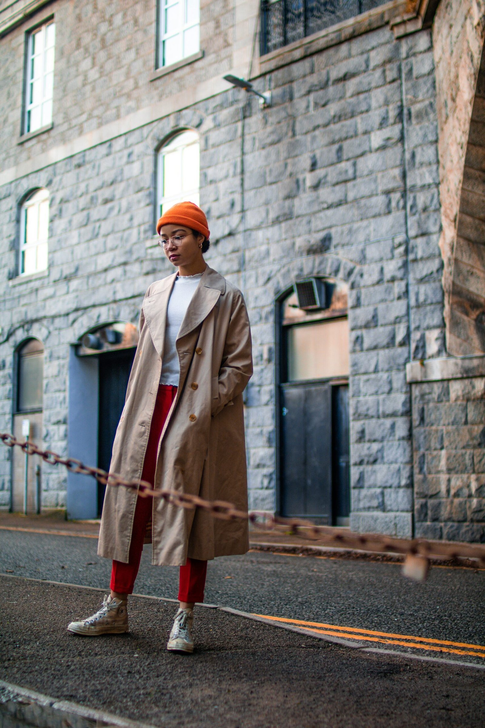 woman wearing brown coat standing besides brown steel chain